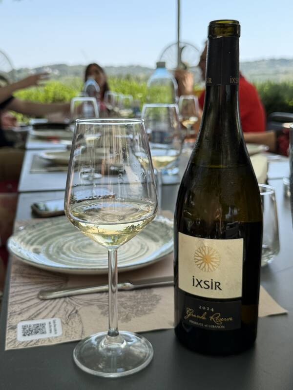 An Ixsir Grande Réserve bottle and a glass of white on the estate terrace